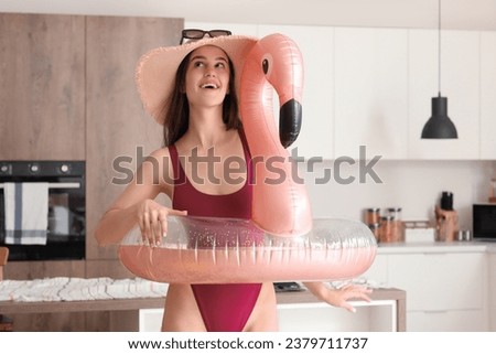 Young woman with swim ring ready for summer vacation in kitchen
