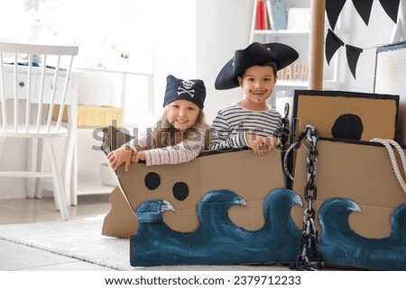 Cute little pirates playing in cardboard ship at home Royalty-Free Stock Photo #2379712233