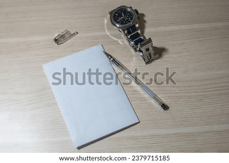 Blank sheet of white paper, pen and wristwatch on a wooden table. Business still life with copy space.