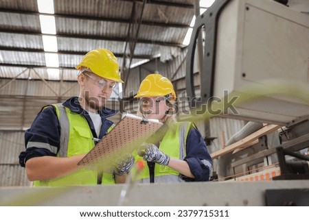 Two dedicated workers in safety attire focus intently on a checklist. Amidst the hum of machinery, they ensure every protocol is met, emphasizing the significance of thorough oversight