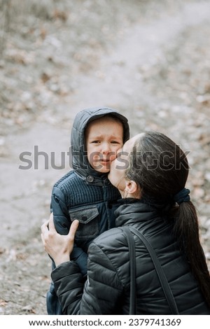 A woman, a mother, hugs and kisses a crying son, boy, child, with love and sympathy. Photography, portrait.