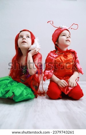 Children in smart carnival costumes on a plain background. Costume of sea fairy creatures. Mermaid and crab. Brother and sister.
