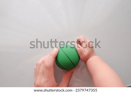 mother and baby playtime with green small basketball, mother and daughter playtime, mother and daughter hand, mother and baby hand grab the green rubber ball,mother daugther quality time
