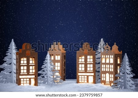 Winter village made of paper. Paper houses in winter city night landscape. Creative Christmas winter background.