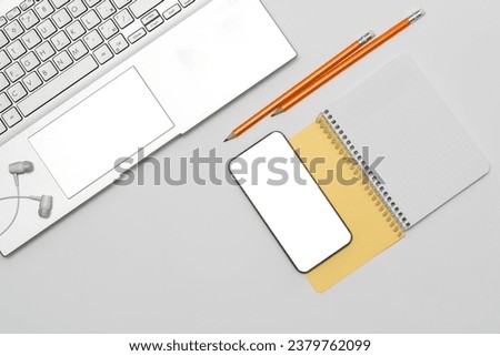 Phone with isolated screen, headphones, laptop, open notebook with space for text, pencils lying on the table. Minimalist mockup with white isolated screen. Education concept, Distance Learning, 