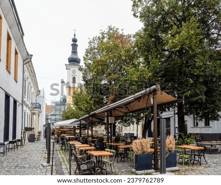 Old town square (Museum's square) in front of the Franciscan Church, Cluj-Napoca Romania. Empty outdoor terrace of a pub in Museum square, Cluj Royalty-Free Stock Photo #2379762789