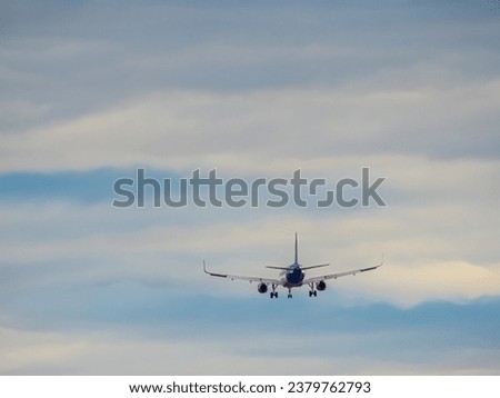 Flying airplane on o cloudy sky. Real plane in the sky view from behind. Royalty-Free Stock Photo #2379762793