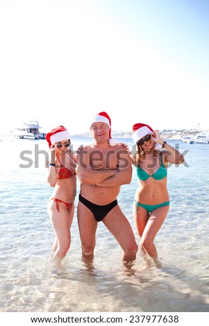 Young company in Santa hats laughing on tropical beach. new year