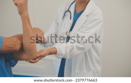 Asian older aged man doing physiotherapist with support from nurse. Senior elderly male sitting on sofa in living room using dumbbells workout exercise for patient with caregiver in nursing care.