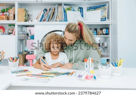 mother and child draw. daughter is engaged in creativity. mother and daughter paint.