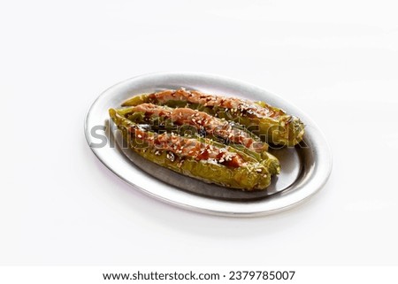 Long grilled green chilies stuffed with ground pork and sauce on a plate on a white background Pictures for designing food menus