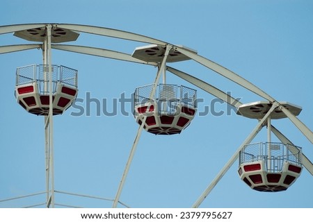 Ferris wheel in an amusement park against a blue sky.