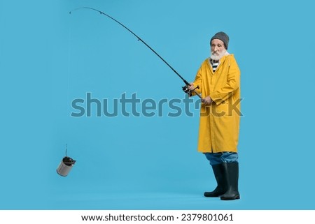 Fisherman with fishing rod and tin can on light blue background, space for text Royalty-Free Stock Photo #2379801061