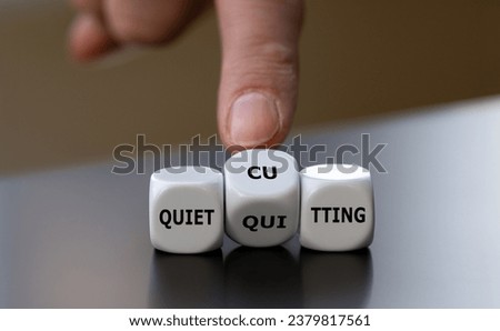Hand turns dice and changes the expression 'quiet quitting' to 'quiet cutting'. Royalty-Free Stock Photo #2379817561