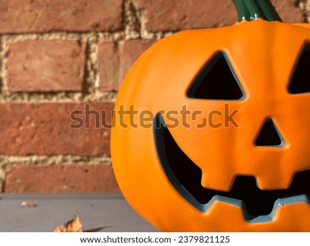Cropped close up of a halloween pumpkin against brick background