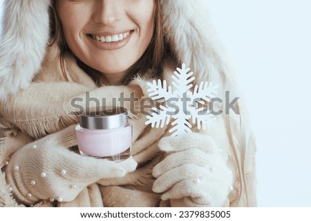Closeup on happy woman isolated on white in white gloves with facial cream and snowflake.