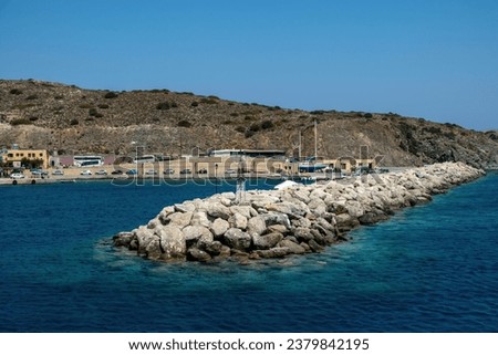 Greece, enjoy Gavdos island, holiday destination Crete. Harbor, ripple sea water, beacon on rocky breakwater, building, summer sunny day. Royalty-Free Stock Photo #2379842195
