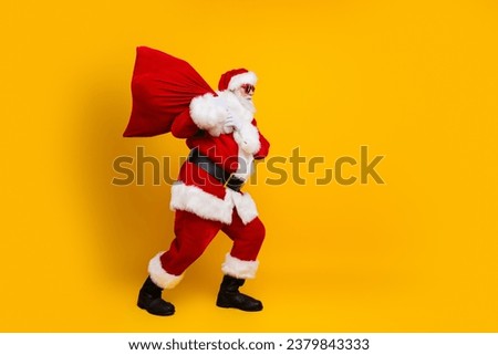 Full body photo of grandfather santa claus carry red sack gifts for kids delivery going to christmas day isolated on yellow color background