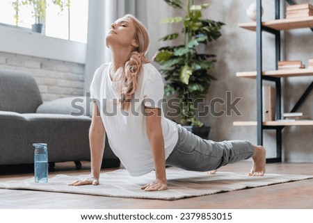 Upward facing dog yoga position. Mature Caucasian woman athlete yogi stretching her body, doing training yoga exercises for muscles to make her body fit and flexible at home Royalty-Free Stock Photo #2379853015