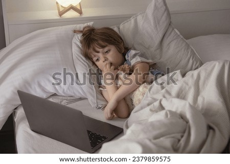 Little boy watch cartoon before a sleeping in the bed. Baby have a call and talking before a sleep on the the laptop. Toddler watch a movie before a sleeping. Laptop before a sleeping.