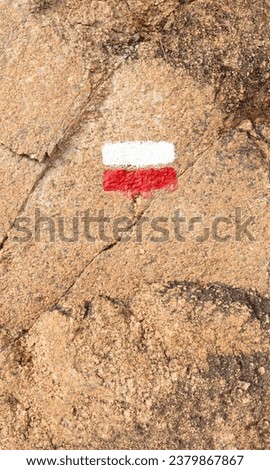 Trail orientation sign painted on rock. Red and white. Vertical.