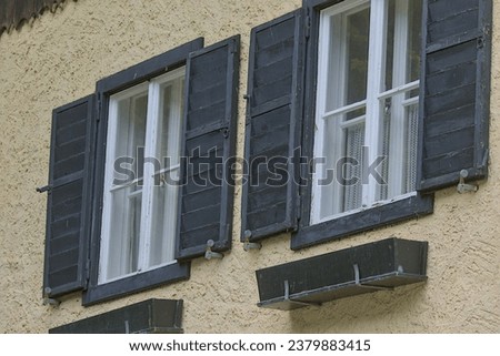 Two antique windows with open wooden shutters in Austria. National village architecture. Historical concept of authenticity. Green tourism.