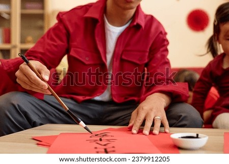 Close up Asian man doing traditional Chinese calligraphy for New Years day with family, copy space Peace and safety wherever you go