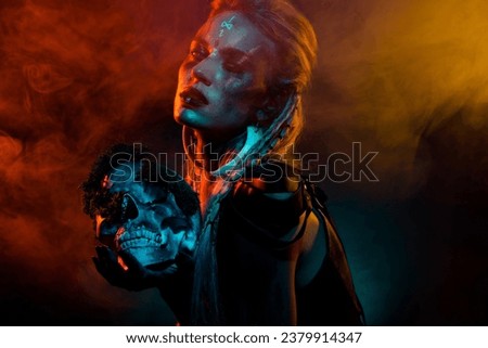 Photo of wild attractive woman wear gothic valkyrie costume holding dead human scull isolated orange fog background