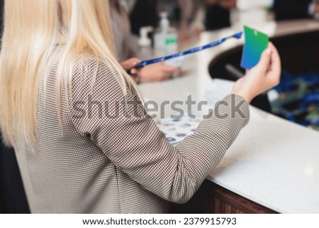 Process of checking in on a conference congress forum event, registration desk table, visitors and attendees receiving a name badge and entrance wristband bracelet and register electronic ticket
 Royalty-Free Stock Photo #2379915793
