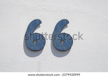 House number 66. Painted iron over whitewashed wall. Houses with personality concept Royalty-Free Stock Photo #2379920999