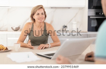 Adult woman while discussing deal with salesman in kitchen at home