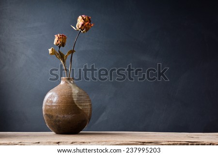 still life photography : Withered rose in ceramic vase on art dark background
