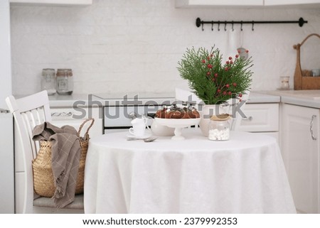 Christmas home interior in white kitchen-Christmas chocolate bundt cake with fresh berries and rosemary. Winter baking at Christmas. Ceramic vase with spruces brunches. High quality photo