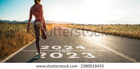 New year 2024 or start straight concept.word 2024 written on the asphalt road and athlete woman runner stretching leg preparing for new year at sunset.Concept of challenge or career path and change.
 Royalty-Free Stock Photo #2380018455