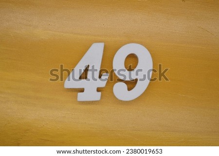 The golden yellow painted wood panel for the background, number 49, is made from white painted wood. Royalty-Free Stock Photo #2380019653
