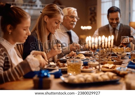 Happy extended family eating dinner while celebrating Hanukkah. Focus is on mother.