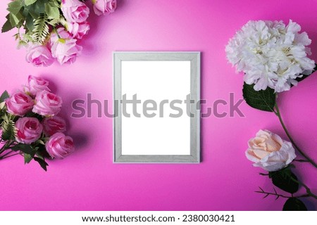 Photo frames and flowers placed on a pink background.