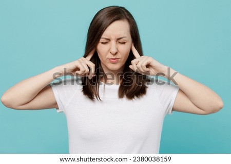 Young woman 20s wear white t-shirt closed eyes cover ears with hands fingers do not want to listen scream isolated on plain pastel light blue cyan background studio portrait. People lifestyle concept Royalty-Free Stock Photo #2380038159