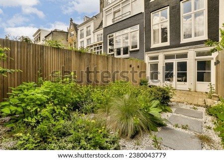 a backyard area with plants and flowers in the foreground, surrounded by a wooden fence that has been used as a planter