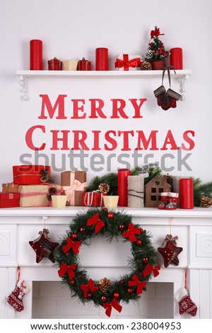 Decorations with Merry Christmas inscription on mantelpiece on white wall background