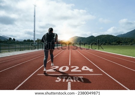 Happy New Year 2024 symbolizes the start of the new year. Woman preparing to run on the athletics track is engraved with the year 2024. start challenge goal of planning health and business to success Royalty-Free Stock Photo #2380049871