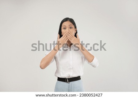 Photo of shocked young asian woman shuts her mouth with startled, impressed face expression, stands over white background. Royalty-Free Stock Photo #2380052427
