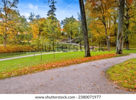 Public old garden park in a sunny autumnal day with gravel pedestrian walkways


