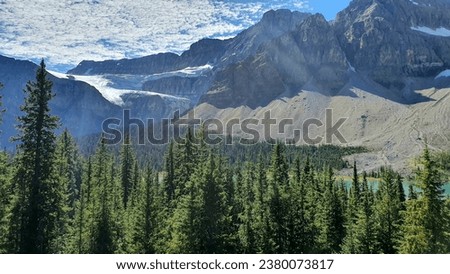 White clouds, glaciers on mountains, forests and tuquoise lake in one photo taken from a peak. Yoho National Park, Alberta, Canada