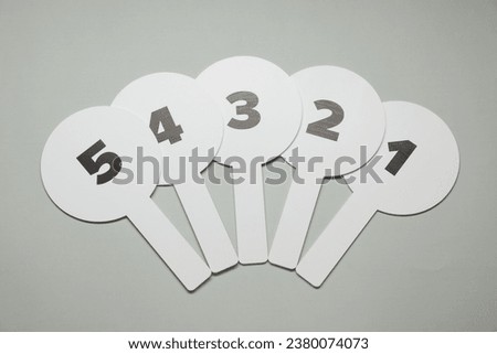 Auction paddles with numbers on light grey background, flat lay