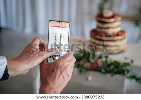 Food photography concept. Blogger taking picture of cake to upload on website. Wedding cake with flowers. Ideas for serving. Picture for a menu or confectionery catalog, restaurant, candy bar