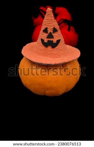 Halloween Pumpkin. Pumpkin with witch hat on a black background. Pumpkins and spiders in blur in the composition. Copy space at the bottom. Halloween card concept.