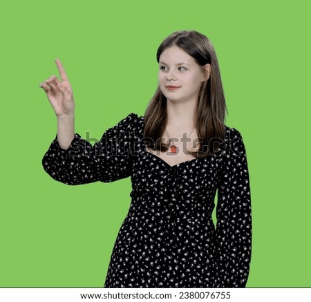 Young charming woman makes finger touching virtual display on green background, Chroma key