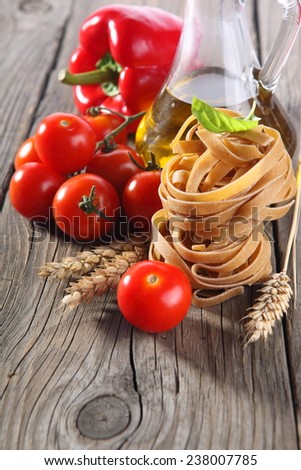 Spaghetti and tomatoes with herbs on an old and vintage wooden table 