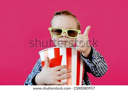 Little cute fun kid baby boy 3-4 years old in red t-shirt holding bucket for popcorn, eating fast food isolated on yellow background. . High quality photo